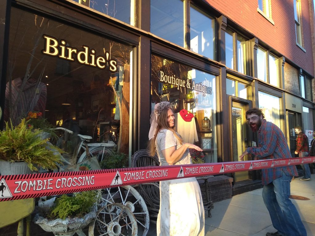 A zombie bride and zombie man in front of Birdie's Boutique.