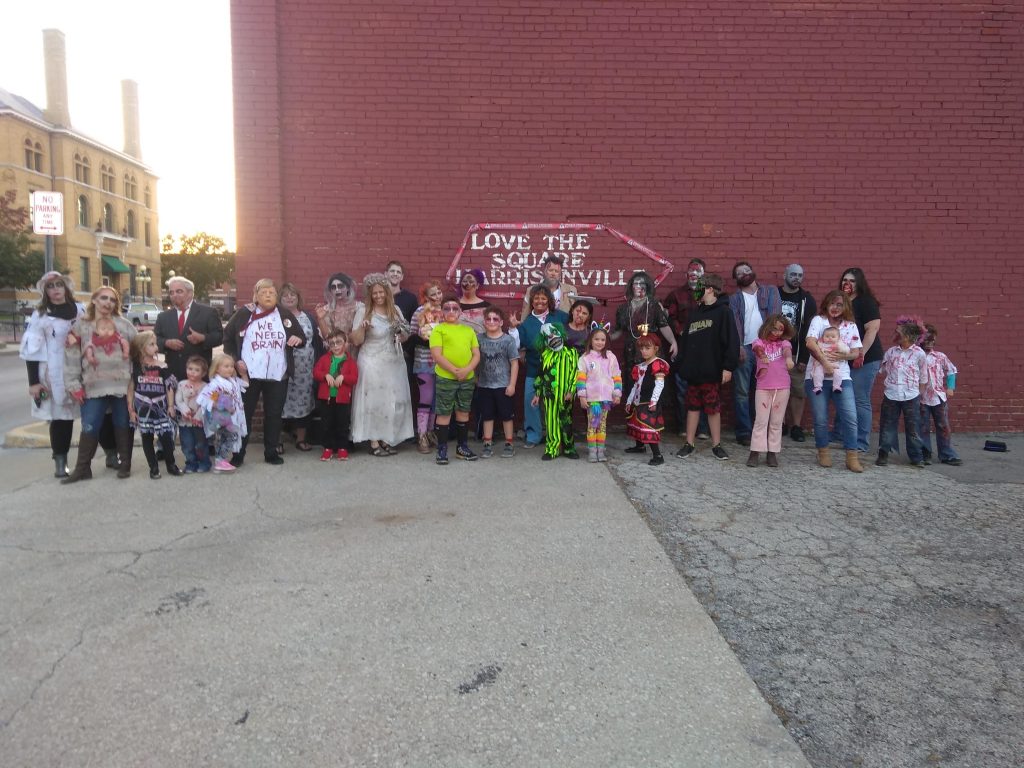 A group photo of zombie in front of a brick wall.